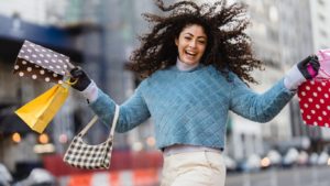 Imagem de uma mulher feliz com algumas sacolas de compras nos braços